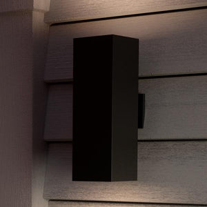 The UHP1112 Minimalist Outdoor Wall Light from the Madrid Collection by Urban Ambiance features a rectangular design in a midnight black finish. Measuring 18 inches high by 6 inches wide, this durable die-cast aluminum fixture is mounted vertically on horizontal siding and casts light both upward and downward, making it ideal for any outdoor setting.