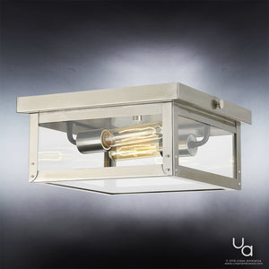The UHP1133 Modern Farmhouse Outdoor Ceiling light from the Darwin Collection by Urban Ambiance, featuring a stainless steel finish and measuring 5-1/2 inches high by 12-3/8 inches wide, is mounted on a white ceiling. Its square design with clear glass panels and exposed tubular bulbs adds nautical-inspired charm to the space, and the Urban Ambiance logo appears in the bottom right corner.