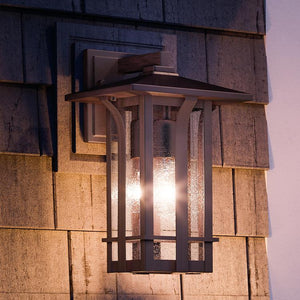 A beautiful Urban Ambiance UHP1153 Craftsman Outdoor Wall Light, 16" x 9", Olde Bronze Finish, Essen Collection on a sandstone wall.