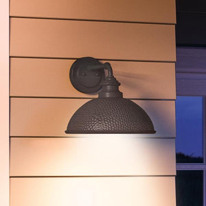 A unique hammered outdoor wall light with an aged pewter finish, from the Firenze Collection, adorns the side of a house.