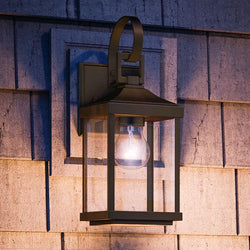 An Urban Ambiance UHP1192 Colonial Outdoor Wall Light, 15-1/8" x 5-1/2", Olde Bronze Finish, Calderdale Collection on the side of a house.