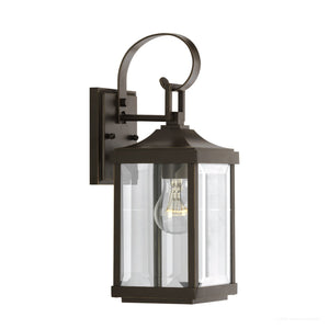 The Urban Ambiance UHP1192 Colonial Outdoor Wall Light from the Calderdale Collection features a rectangular clear beveled glass enclosure, a metal frame with an Olde Bronze finish, a visible bulb design, a curved top arm, and a flat wall plate. It measures 15-1/8″ by 5-1/2″.