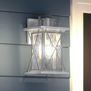 A beautiful Urban Ambiance UHP1223 Colonial Outdoor Wall Light, with a stainless steel finish, adorning the wall of a house.