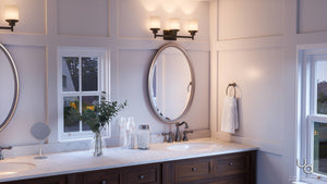 A modern bathroom featuring double sinks, a marble countertop, oval mirrors, and a towel ring is beautifully illuminated by the Urban Ambiance UHP2013 Contemporary Bathroom Vanity Light from the Cupertino Collection in an Olde Bronze finish. Stylish vases and a window framing views of trees outside add to the serene ambiance, while this 9.4375″ high by 22″ wide lighting fixture highlights the elegant bath fixtures and creates a warm, inviting atmosphere.