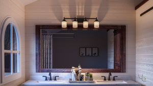 A double sink bathroom vanity features a large framed mirror, contemporary vintage design, and is illuminated by the Urban Ambiance UHP2015 Contemporary Bathroom Vanity Light from the Cupertino Collection in an Olde Bronze finish (9.4375″H x 31″W) mounted above, with toiletries arranged on the counter.