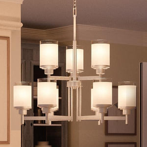 The Urban Ambiance UHP2021 Contemporary Chandelier from the Cupertino Collection features eight frosted glass cylindrical lampshades and a sleek brushed nickel finish. Measuring 28.5 inches high by 28 inches wide, this elegant metal fixture hangs gracefully from the ceiling, adding a sophisticated touch to any residential interior with its neutral finish and modern design.