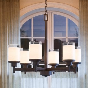 A unique contemporary chandelier from the Cupertino Collection is hanging over a window in a living room.