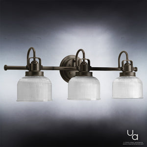 The UHP2044 Luxe Industrial Bath Fixture from Urban Ambiance’s Harlow Collection features three prismatic, ribbed glass shades and a metal frame in a Fashion Bronze finish, mounted on a round wall plate and measuring 8-3/4″H x 26-1/4″W.