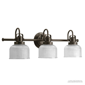 The UHP2044 Luxe Industrial Bath Fixture from Urban Ambiance’s Harlow Collection features a Fashion Bronze finish, three clear prismatic glass shades, and is mounted on a round wall plate—measuring 8-3/4″ high by 26-1/4″ wide—for an industrial-inspired vanity lighting solution.