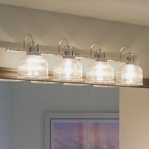 Four prismatic glass shades are mounted on the UHP2046 Luxe Industrial Bath Fixture from Urban Ambiance’s Harlow Collection, featuring a polished chrome finish and measuring 8-3/4″ high by 35-1/2″ wide. Installed above a bathroom mirror with all lights illuminated, it creates a striking industrial bath light effect.