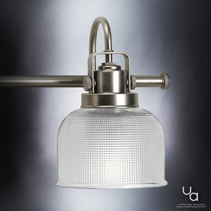 Close-up of the Urban Ambiance UHP2048 Luxe Industrial Bath Fixture from the Harlow Collection, showcasing its aged nickel finish and ribbed prismatic glass shade against a gradient gray background; fixture measures 8-3/4″ high by 35-1/2″ wide.