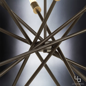 Close-up view of intersecting metal rods from the Urban Ambiance UHP2070 Modern Industrial Chandelier (Miami Collection, 19-5/8″H x 42-3/8″W), featuring exposed bulbs and an Olde Bronze finish, set against a soft gradient background—a striking example of modern vintage lighting.