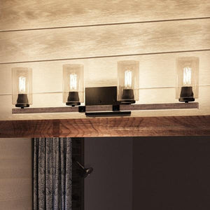 The Urban Ambiance UHP2082 Vintage Bath Fixture from the Darlington Collection, featuring four seeded glass shades and an Olde Bronze finish, is mounted on a wood-inspired bar above a window adorned with patterned curtains.