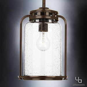 The UHP2111 Nautical Pendant Light from Urban Ambiance’s Carlsbad Collection features a 12″ high by 7.75″ wide clear seeded glass shade with visible bubbles, an Olde Bronze finished frame, and an exposed bulb design, shown here against a neutral background.