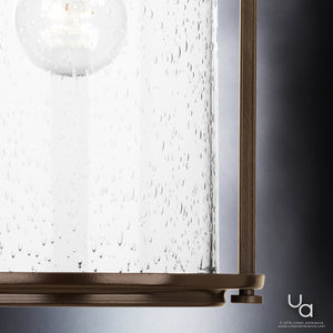 Close-up of the Urban Ambiance UHP2111 Nautical Pendant Light from the Carlsbad Collection, showcasing its cylindrical seeded glass with water droplet textures and an Olde Bronze-finished frame accenting the bottom and sides.