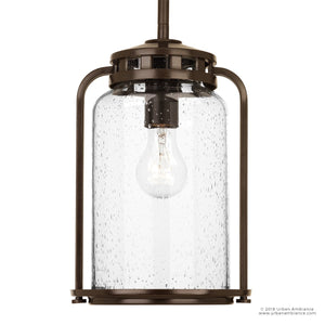 The UHP2111 Nautical Pendant Light from the Carlsbad Collection by Urban Ambiance features an Olde Bronze frame paired with a clear seeded glass shade, showcasing an exposed bulb inside for a bold modern accent. Measuring 12 inches high by 7.75 inches wide, this fixture brings striking style to any space.