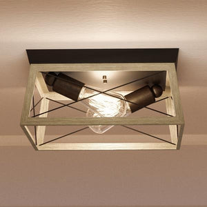 Add a touch of vintage industrial style to your modern rustic lighting scheme with the Urban Ambiance UHP2121 Luxe Industrial Flush-Mount Ceiling Fixture from the Berkeley Collection, featuring a rectangular wooden frame, metal accents in a charcoal finish, and two exposed bulbs arranged diagonally inside. Measures 6″ high by 12″ wide.