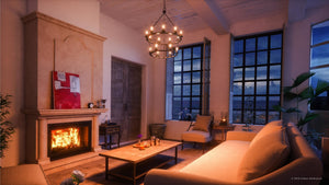 A cozy living room featuring a lit fireplace, illuminated by the UHP2247 XL Industrial Chandelier from Urban Ambiance’s Nashville Collection (41-5/8″ x 36″, Charcoal Finish). The space includes two large windows with evening light outside, a sofa, armchairs, coffee table, and artwork displayed above the mantle.