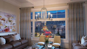 Modern living room with brown sofas, a glass coffee table, large window overlooking the city at dusk, and the UHP2252 Mediterranean Chandelier from Urban Ambiance’s Lexington Collection (24″H x 28″W, Antique Silver Finish) adorned with crystal strands hanging from the ceiling.