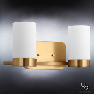 The Urban Ambiance UHP2291 Contemporary Bathroom Vanity Light from the Madison Collection features a brushed bronze finish and two cylindrical white glass shades. This modern fixture, measuring 7.5″ in height and 15.375″ in width, is styled with open-frame influences and displayed here against a gradient gray background.