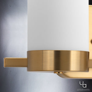 Close-up of the Urban Ambiance UHP2291 Contemporary Bathroom Vanity Light from the Madison Collection, showcasing a frosted cylindrical glass shade and a brushed bronze metal base, set against a gradient gray background.