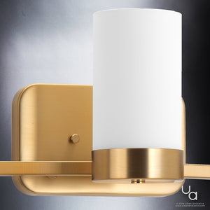 The UHP2293 Contemporary Bathroom Vanity Light from Urban Ambiance’s Madison Collection, featuring a brushed bronze finish and a sleek cylindrical white glass shade, is elegantly wall-mounted and photographed against a gray background—offering a touch of understated sophistication reminiscent of an antique silver chandelier.