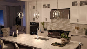 Modern kitchen with white cabinets, marble island, stainless steel appliances, and the Urban Ambiance UHP2320 Luxe Industrial Pendant from the Arezzo Collection, featuring a brushed nickel finish and interlocking steel rings for a contemporary touch. A bowl of greens sits on the counter while a living area is visible in the background.