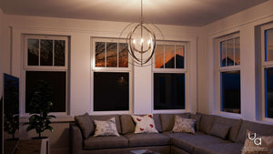 A living room with large windows and a UHP2329 Industrial Chic Chandelier, 30