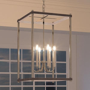 A unique lighting fixture, the Urban Ambiance UHP2381 Modern Farmhouse Narrow Chandelier with a brushed nickel finish from the Leeds Collection creates a luxury ambiance as it hangs over a window in a