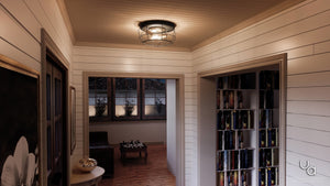 A hallway with white shiplap walls, a bookshelf, a painting, and an adjoining room featuring a chess table by the window is illuminated by the Urban Ambiance UHP2423 Vintage Ceiling Fixture from the Syracuse Collection. This modern industrial light showcases an open cage design and a charcoal finish, measuring 6.75 inches high by 14 inches wide.