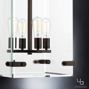 Close-up of the Urban Ambiance UHP2442 Modern Farmhouse Modern Chandelier from the Bristol Collection, featuring exposed Edison bulbs and black metal accents in an Olde Bronze finish. Measuring 28-3/8″ high by 14-3/4″ square, this striking fixture is mounted against a white and dark gray background. Its design blends classic farmhouse charm with contemporary style for a refined modern aesthetic.