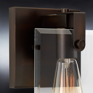 Close-up of the Urban Ambiance UHP2454 Modern Farmhouse Bath / Wall Light from the Bristol Collection, showcasing its Olde Bronze finish, beveled glass panel, and exposed filament bulb against a dark background.