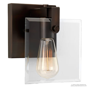 The Urban Ambiance UHP2454 Modern Farmhouse Modern Bath/Wall Light from the Bristol Collection features a clear beveled glass panel, an exposed vintage-style bulb, and a dark metallic fixture with an elegant Olde Bronze finish. It measures 8-3/8 inches high by 7 inches wide.