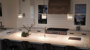 A kitchen with a large island and stools featuring the UHP2461 Crystal Pendant, 11-1/4