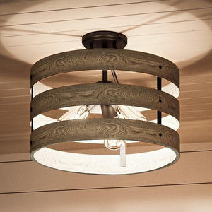 Close-up of the UHP2470 Modern Farmhouse Flush-Mount Ceiling Fixture from Urban Ambiance’s Adelaide Collection—measuring 13-1/2″ high by 17″ wide, with exposed bulbs encircled by three horizontal wooden bands in a charcoal finish, mounted on a white paneled ceiling.