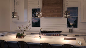 A modern kitchen featuring a marble island, wooden accents, and a UHP2472 Modern Farmhouse Pendant from the Adelaide Collection by Urban Ambiance (10″H x 8-1/2″W, Charcoal Finish) above the workspace, complemented by a gas stove and two windows with views of the evening sky.