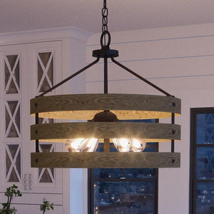 The UHP2474 Modern Farmhouse Chandelier from the Adelaide Collection by Urban Ambiance features a round wooden drum design with three horizontal slats, sturdy metal supports, and exposed bulbs. Measuring 18-1/4″ high and 21-5/8″ wide in a charcoal finish, this chandelier brings an industrial rustic charm as it hangs from the ceiling in any modern kitchen.