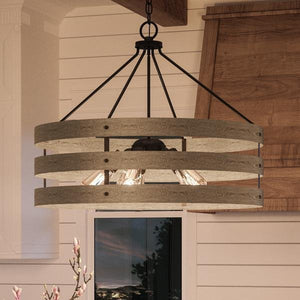 The UHP2478 Modern Farmhouse Chandelier from Urban Ambiance’s Adelaide Collection, featuring a 22-3/4″ tall by 27-3/4″ wide open cage design in a charcoal finish with exposed bulbs, hangs from the ceiling of a room adorned with white paneled walls and wooden accents.