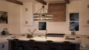 A modern kitchen featuring a spacious island with bar stools, white cabinetry, shiplap walls, and a wooden light fixture. Suspended above the island is the Urban Ambiance UHP2478 Modern Farmhouse Chandelier from the Adelaide Collection, showcasing an open cage design in a charcoal finish that adds rustic charm. Large windows and potted plants adorn the counter.