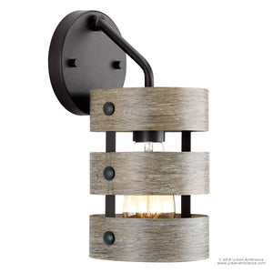 The UHP2480 Modern Farmhouse Bath / Wall Light by Urban Ambiance features a charcoal finish with a round base and two horizontal, weathered wood-inspired bands encasing an exposed bulb, adding farmhouse-inspired charm to any space. Part of the Adelaide Collection, this 12″ high by 6″ wide wall sconce is a stylish addition to rustic or modern bathrooms.