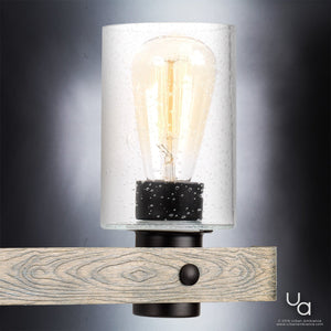 The Urban Ambiance UHP2484 Modern Farmhouse Bath Fixture from the Adelaide Collection, featuring a charcoal finish and measuring 8-1/2″ high by 24″ wide, showcases a clear glass shade with a visible filament bulb and an open cage design mounted on a wood-textured metal arm against a neutral background.