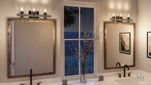 Two mirrors above a double sink with black faucets, the Urban Ambiance Adelaide Collection UHP2484 Modern Farmhouse Bath Fixture in a Charcoal Finish, a vase with branches, and a window revealing a nighttime scene.