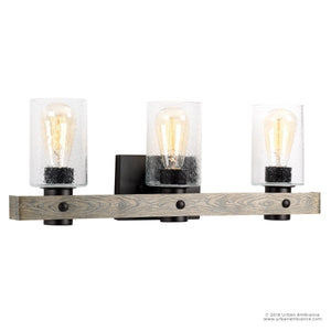 The UHP2484 Modern Farmhouse Bath Fixture from the Adelaide Collection by Urban Ambiance features three clear glass shades, Edison bulbs, and a rectangular charcoal base with a horizontal wood accent bar. Measuring 8-1/2 inches high by 24 inches wide, this stylish light brings modern farmhouse charm and rustic elegance to any space.