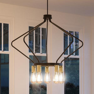 The UHP2492 Mid-Century Modern Industrial Chandelier from the Palma Collection by Urban Ambiance features a striking geometric black metal frame in an olde bronze finish and exposed bulbs, elegantly suspended in front of large windows.