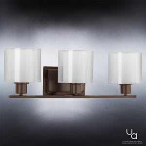 The UHP2513 Cosmopolitan Bathroom Vanity Light from the Tacoma Collection by Urban Ambiance features three frosted cylindrical glass shades mounted on a rectangular Olde Bronze base, offering a modern yet timeless look at 7.375″ high and 23.5″ wide.