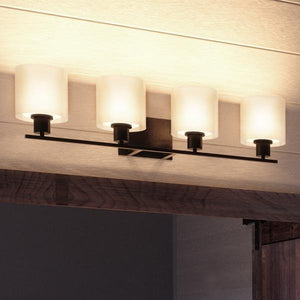 The Urban Ambiance UHP2515 Cosmopolitan Bathroom Vanity Light from the Tacoma Collection features four evenly spaced cylindrical Mylar shades mounted on a horizontal metal bar in an elegant Olde Bronze finish, creating a modern illuminated wall fixture.