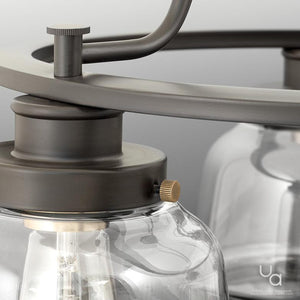 Close-up of the Urban Ambiance UHP2531 Luxe Industrial Chandelier from the Nottingham Collection, showcasing its round frame in an Olde Bronze finish with clear glass shades—a detail view highlighting the fixture’s screw detail and part of the light bulb inside.
