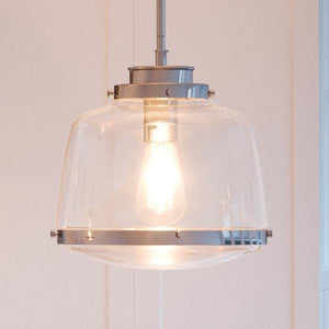 An UHP2534 Industrial Chic Pendant Light, a unique lighting fixture, hangs above a white kitchen.