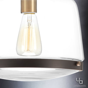 A unique lamp from the Nottingham Collection by Urban Ambiance, featuring an UHP2535 Industrial Chic Pendant Light with a glass shade and a brass base, adding a touch of luxury.
