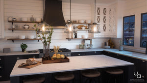 A stunning kitchen with white cabinets and black counter tops, beautifully enhanced by the UHP2535 Industrial Chic Pendant Light from Urban Ambiance's Nottingham Collection.